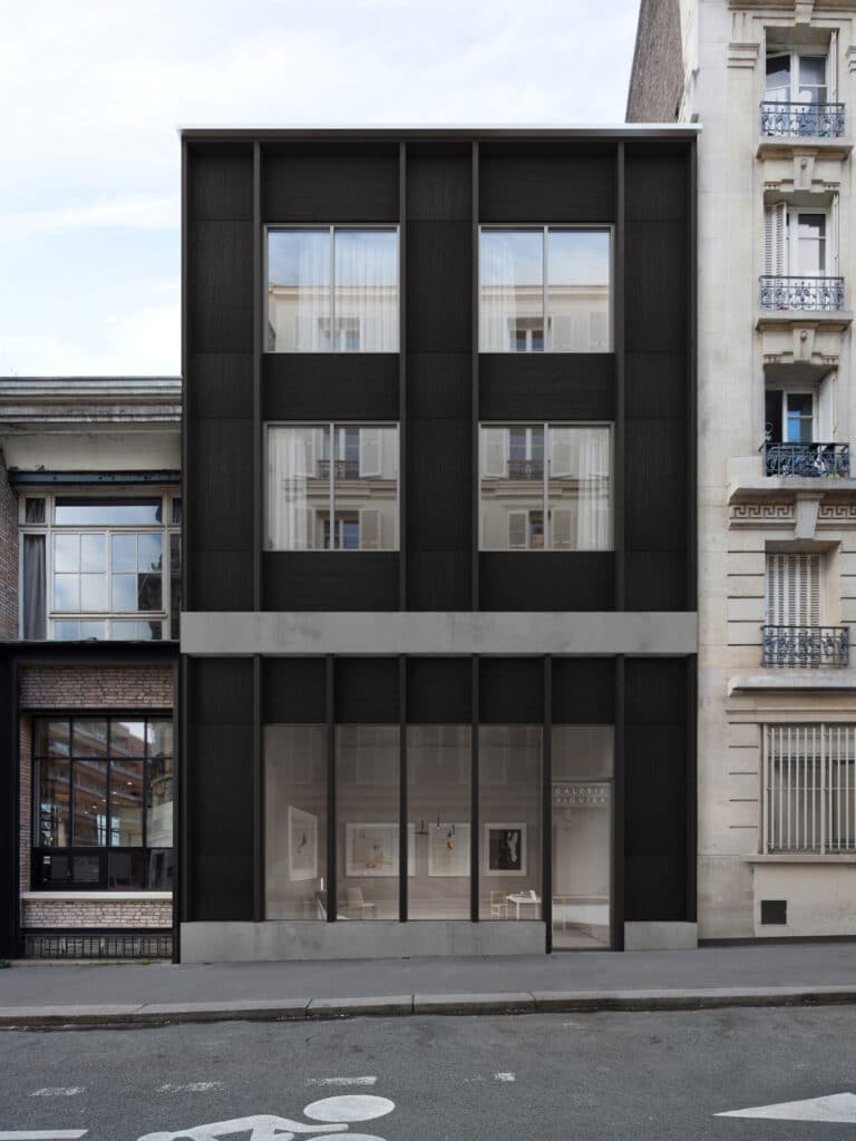 Revestimiento exterior Parklex Prodema impermeable y que no requiere mantenimiento, con una textura de madera natural en color negro para la fachada exterior de una galería.